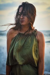 Mid adult woman standing at beach against sky