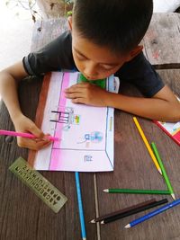 High angle view of girl holding paper on table
