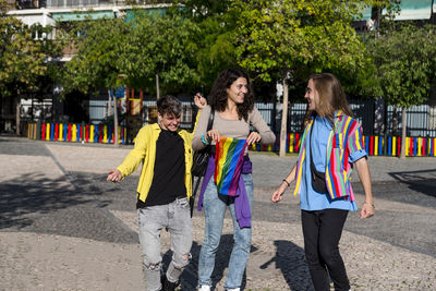 Young diverse friends walking on the street with the lgbt rainbow flag.