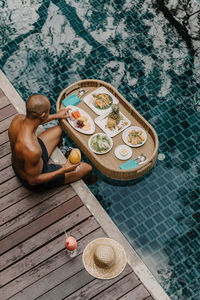 High angle view of shirtless man having food on swimming pool