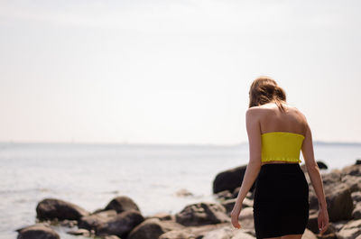 Rear view of woman looking at sea shore against sky