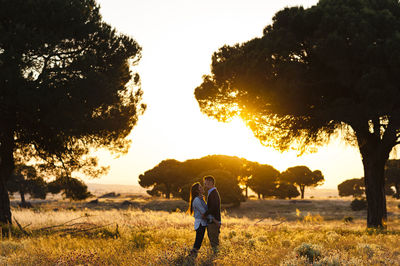 Men standing on field against sky during sunset