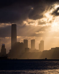 Sea by buildings against sky during sunset