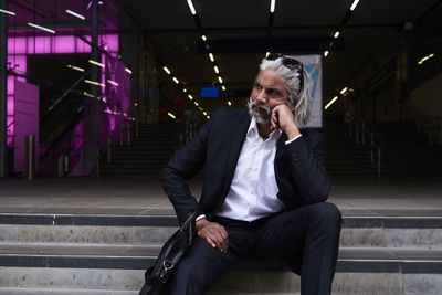 Stylish senior businessman sitting on stairs outdoors