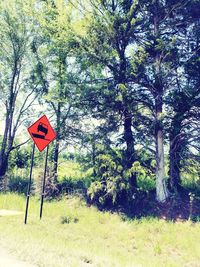 Road sign by trees on field