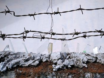 Snow on barbed wire against sky during winter