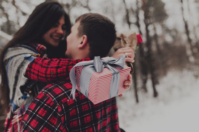 Boyfriend giving a gift box present with ribbon outdoor due to saint valentine day to her girlfriend