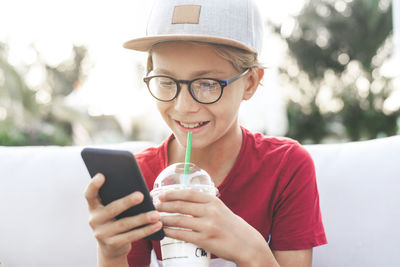 Close-up of boy having drink and using phone