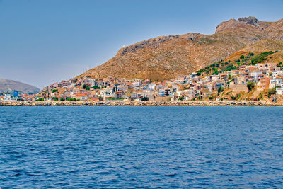 Scenic view of sea by buildings against clear blue sky