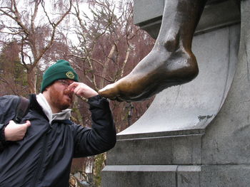 Man holding nose by wet foot statue