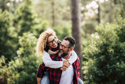 Portrait of smiling young woman against trees