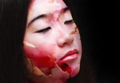 Close-up of young woman against black background