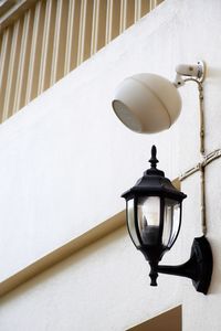 Vintage style lamp with loudspeaker on the building beside the wall of the building.