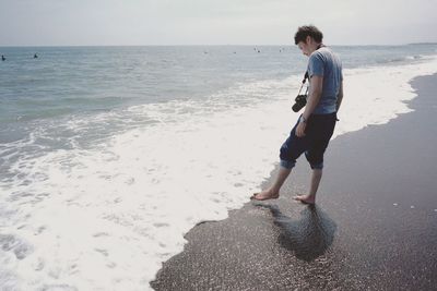 Full length of man standing on shore at beach