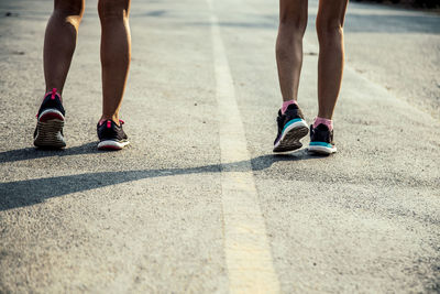 Low section of female friends walking on road