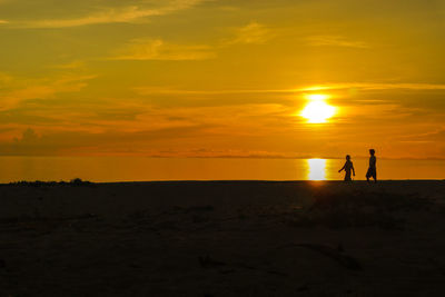 Silhouette people standing on land against sky during sunset