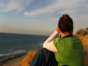 Rear view of woman sitting on shore at beach