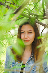 Portrait of beautiful woman standing by plant