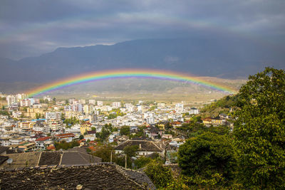Rainbow over city against sky