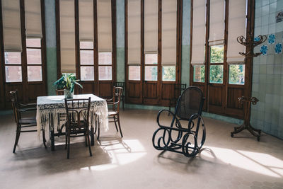 Empty chairs and table against window