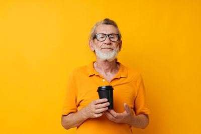 Portrait of young woman using mobile phone against yellow background