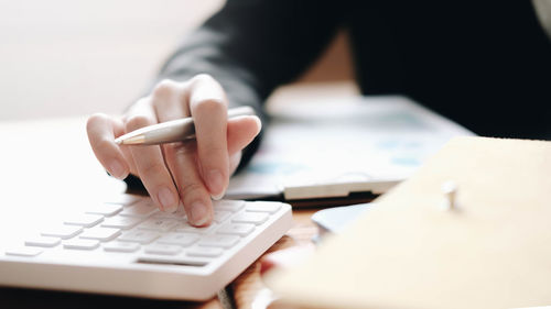 Midsection of person using mobile phone on table