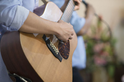 Midsection of man playing guitar