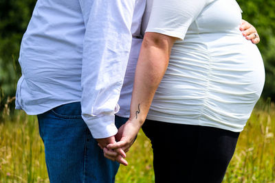 Midsection of man holding hands of pregnant woman