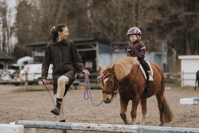 Girl horseback riding with female instructor walking along her