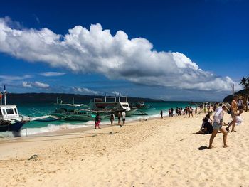 Panoramic view of people on beach against blue sky