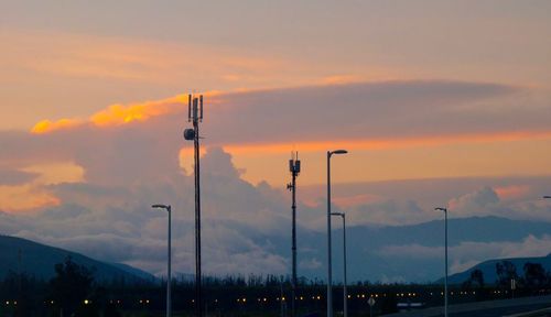 Silhouette street lights against sky during sunset