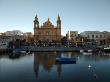 Boats in canal by buildings in city