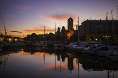 Sailboats moored in canal against sky during sunset