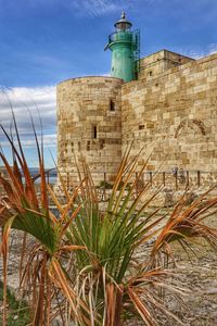 Lighthouse by sea against sky