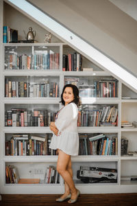Portrait of smiling young woman standing in shelf