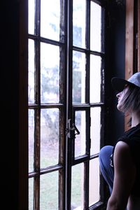 Woman looking through window at home