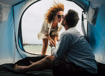 Woman kissing man sitting in tent