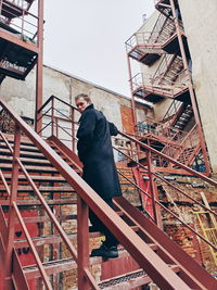 Low angle portrait of man moving up on steps against building