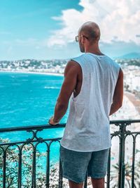 Rear view of man looking at sea against sky