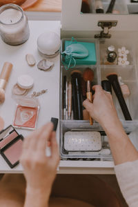 Cropped hands of woman holding beauty products on table at home