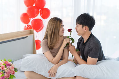 Couple sitting on balloons at home