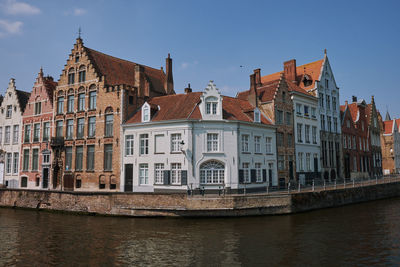 Buildings by river against sky, brugge, belgium