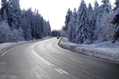 Road amidst trees against clear sky during winter