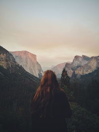 Rear view of woman standing on mountain against sky