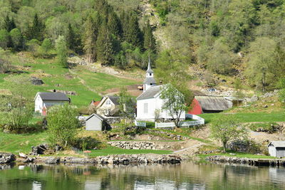 Houses by lake and buildings against trees