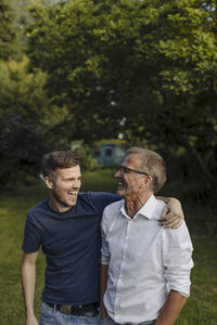Laughing son embracing father while standing at backyard