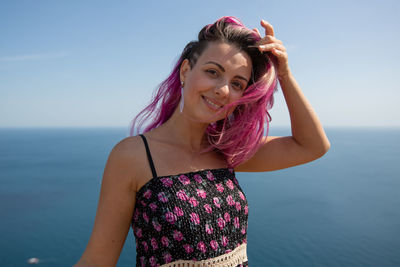 Portrait of smiling woman against sea and sky