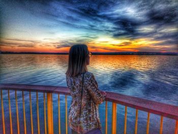 Rear view of woman standing by railing against sea