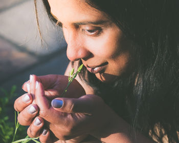 Close-up of woman smelling plant growing on field