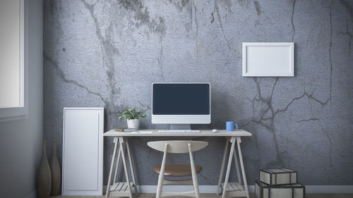 Empty chairs and table against wall